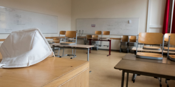 FFP2 Maske liegt auf dem Lehrerpult einen leeren Klasse