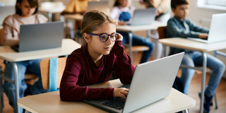 Grundschulkinder arbeiten in ihrem Klassenraum an Laptops