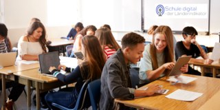 Foto eines Klassenzimmers mit Schülerinnen und Schülern an Laptops, sowie dem Logo des Projekts in der oberen, rechten Ecke