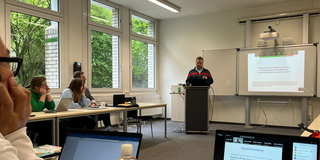 Workshop Becker Michael Becker hält vor einer Gruppe von Personen eine Workshop