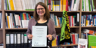 Justine Stang-Rabrig startet als Juniorprofessorin und präsentiert ihre Urkunde.