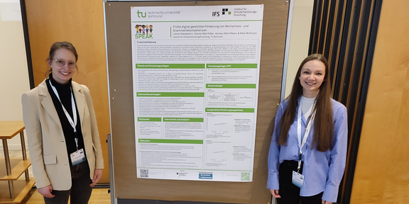 Foto von Svenja Wehrhöfer und Leonie Dargiewicz neben einem Poster des Projekts SPEAK