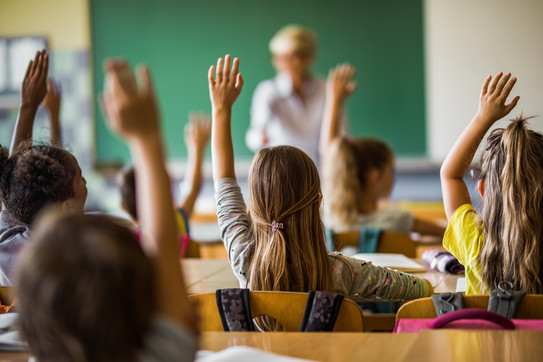 Abstimmung Schülerinnen und Schüler stimmen im Klassenraum mit Handzeichen ab