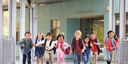 Gruppe von Grunschulkindern läuft auf einem Flur